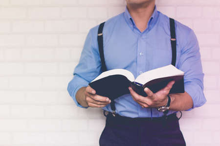 close up. Young handsome Asia businessman reading a book while standing in room.vintage tone,Selective focus.の写真素材