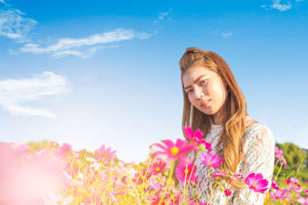 Blur.Portrait. Asian Beautiful girl smiling standing in cosmos flower garden with sunset light , park outdoor.の写真素材