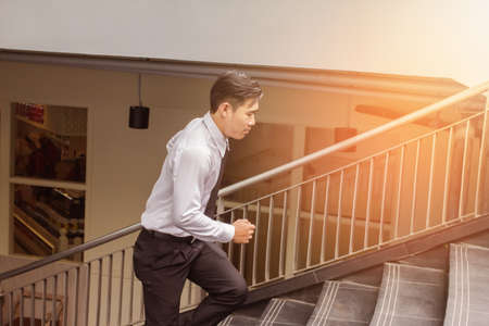 Young Asian Businessman running on stairs, rushing to office service. Outdoor, light sunset...
