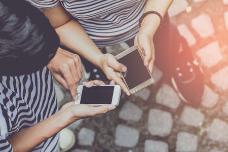 Close up of man and woman hands holding touching mobile phone with blank copy space for your text message on the road  with light Sunset,Vintage tone.Selective focusの写真素材