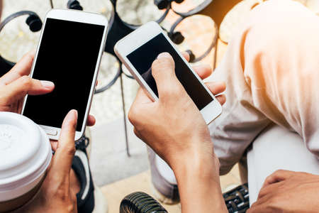 Close up of men and woman hands holding touching mobile phone with blank copy space for your text...