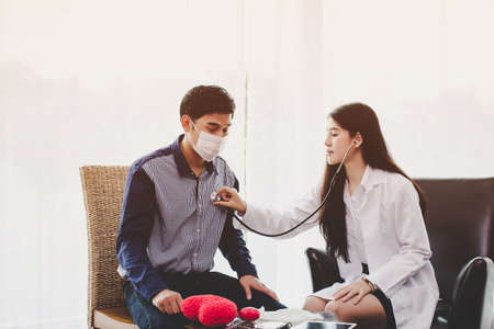 Asian female doctor examines heartbeat and talk about the health problems of the respiratory system of men.の写真素材