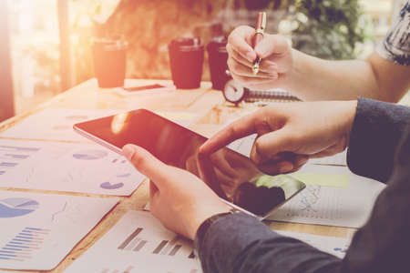 Start up business. people meeting point to discuss the graph up and down of the economy and work on tablet.Soft Focusの写真素材