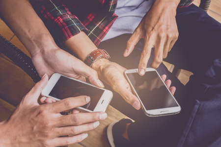 Close up of men and  hands holding touching mobile phone with blank copy space for your text message in cafe  with light Sunset,Vintage tone.Selective focusの写真素材