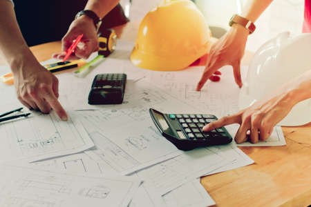 Close up man hand using calculator Calculating bonus(Or other compensation) to employees to increase productivity.Writing paper on deskの写真素材