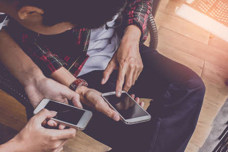 Close up of men hands holding touching mobile phone with blank copy space for your text message in cafe with light Sunset,Vintage tone.Selective focusの写真素材