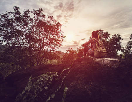 A woman sitting looking at mountain in the evening hiking.Natural and cool. Lamphun, Thailand.With grain.Selective Focusの写真素材