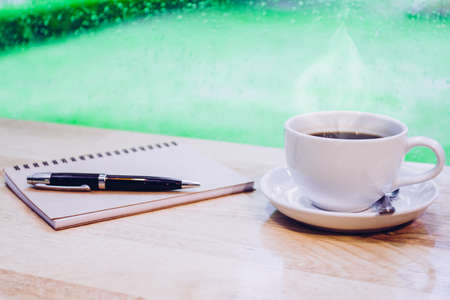 Coffee cup with smoke,work desk with pen and notebookの写真素材