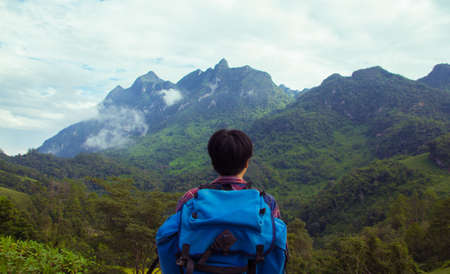 Rear view of an Asian young man in Scottish shirt and backpack at mountain peak above clouds and fog Hiker outdoor. Doi Luang Chiang Dao Chiang Mai Province in the morning.の写真素材