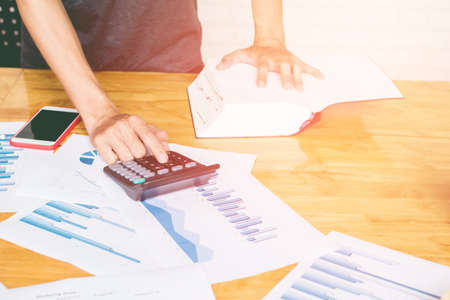 Close up man's hand using calculator Calculating bonus (Or other compensation) to employees to increase productivity. Writing paper on desk. Selective Focusの写真素材