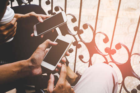 Close up of men and woman hands holding touching mobile phone with blank copy space for your text message in cafe,Vintage tone.Selective focusの写真素材