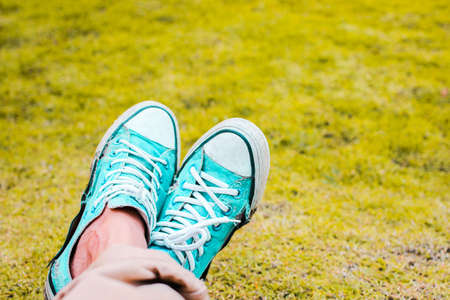Close-up of teenager wearing green sneakers pastel on grass backgroundの写真素材