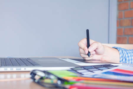 Designer graphic creative ,holding Mouse pen,working laptop in  office with sunset...