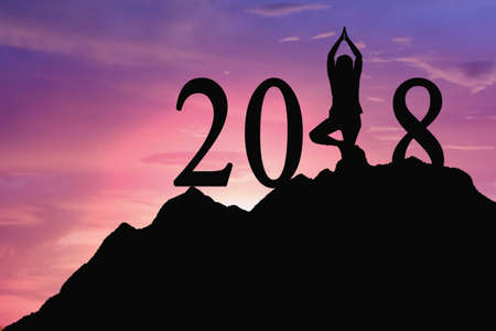 Silhouette. Young woman standing, yoga on mountain, for 2018 new year. Future with sunset light concept.の写真素材