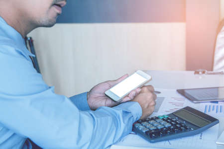 Asian young businessman holding mobile phone chat Meetings the commercial processes involved in promoting and selling and distributing a product or serviceの写真素材