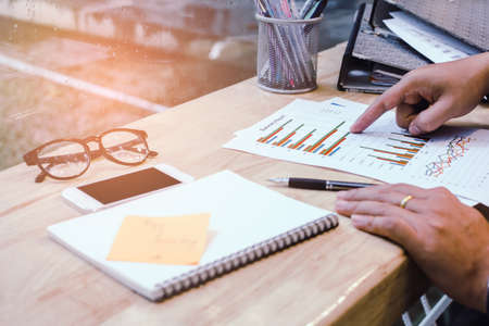 Businessman in black shirt hands holding pen pointing at business document on desk with sunset back. business concept.の写真素材
