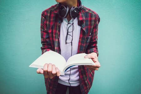  University students in scot shirt and Headphones.Man standing on green background. Reading  book and relaxing. Selective Focus.の写真素材