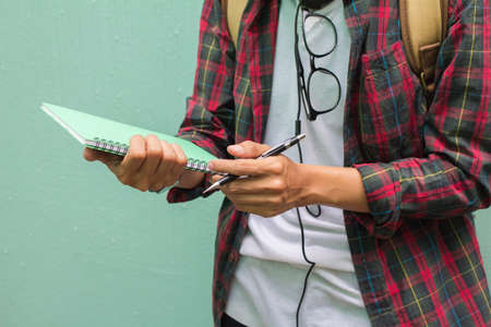 Education Concept. Man in Scottish shirt.Holding green notebook Waiting studying,learning ,Tutor books with friends.On green background.Selective focusの写真素材