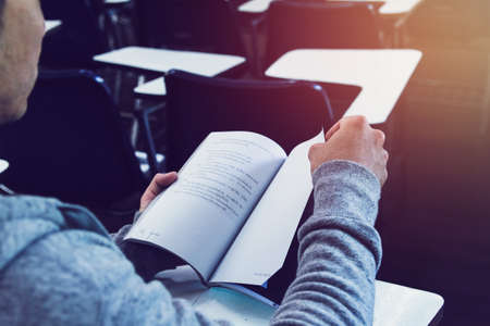 Man in black shirt and gray Hooded sweatshirt sitting  reading book test on table ,Copy space for...
