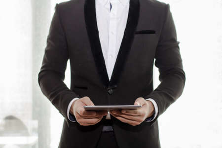 Businessman in black suit hand holding tablet on coffee shop.Copy space fore your textの写真素材