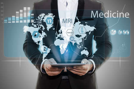 Businessman in black suit hand holding tablet . Medical infographics On gray background empty virtual screen, modern Health Care and Medical  concept の写真素材