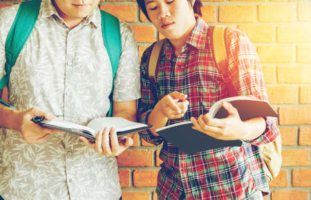 Asian young man,Homosexuality or woman pointing studying examining. Tutor books with friends. Young students campus helps friend catching up and learning. People, learning, educationの写真素材