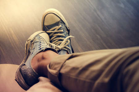  Man wearing old blue sneakers in brown trousers sitting on coffee shop,Vintage tone.Selective focusの写真素材