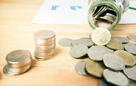 Coins or Thai Baht coins, stacks of coins, wood table with sunset light background