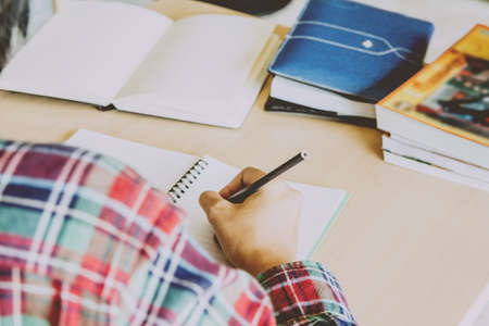 Close- up.School student holding pencil taking exams writing in classroom for education concept with sunset light backgroundの写真素材