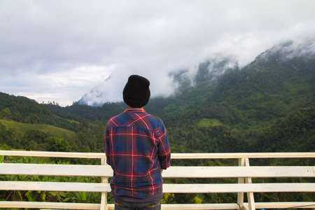Asian young man in Scottish shirt and black hat hiking at mountain peak above clouds and fog Hiker outdoor. Doi Luang Chiang Dao Chiangmai Province,In morning.の写真素材