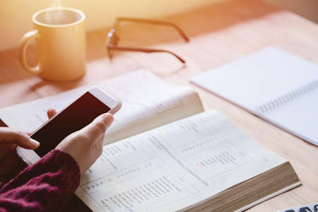 Close up of  woman hands holding touching mobile phone with blank copy space for your text message in home  with light Sunset,Vintage tone.Selective focusの写真素材