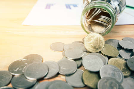 Coins or Thai Baht coins, stacks of coins, wood table with sunset light background