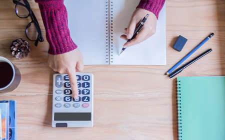 Top view. Hand woman doing finances and calculating on table  at home office.Concept finances and...