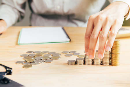 handles coins placed on a pile of money on the table with light Sunset's business concept.の写真素材