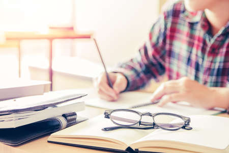 Close- up.School student holding pencil taking exams writing in classroom for education concept with...