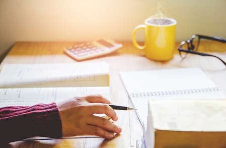 Close- up.School student holding pencil taking exams writing in classroom for education concept with sunset light backgroundの写真素材
