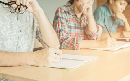 Asian young man,Homosexuality or woman holding pencil exam,examination in classroom . Tutor books with friends. Young students helps friend and learning. People, learning, education.の写真素材