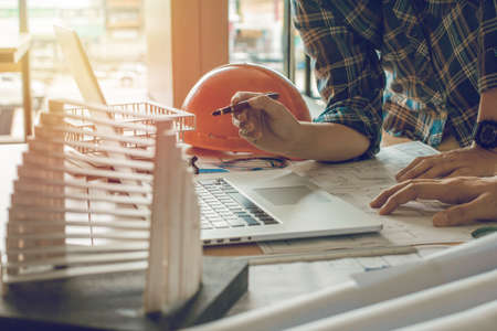 Concept architects,engineer holding pen pointing equipment architects On the desk with a blueprint in the office, Vintage, Sunset light.Selective Focusの写真素材