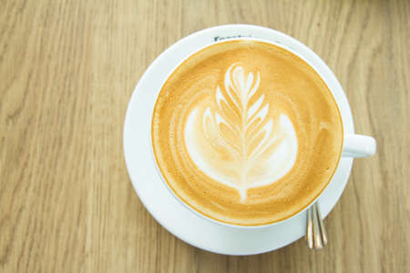Top view. Hot coffee cup latte art on wood table