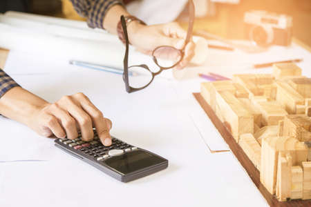 Close up man hand using calculator Calculating bonus(Or other compensation) to employees to increase productivity.Writing paper on desk.Selective Focusの写真素材
