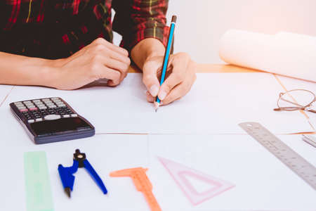 Concept architects,engineer holding pen pointing equipment architects On the desk with a blueprint in the office, Vintage, Sunset light.Selective Focusの写真素材