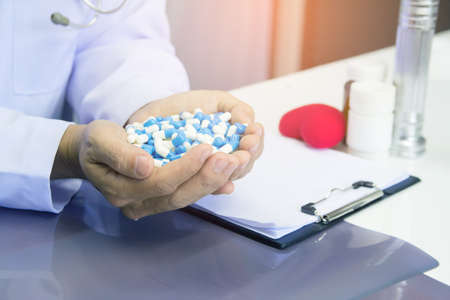 Healthcare and medical concept . Doctor in uniform holding white and blue capsule pill in office at hospital,Selective focusの写真素材