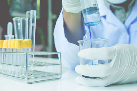 Close up. Medical or male medical in laboratory room research performs tests with blue liquid, Experimental Drug Treatmentの写真素材