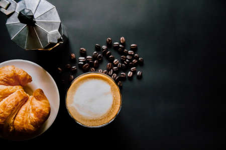 Latte art ,Croissant and moka pot with Roasted coffee on black background in the morning top view and  vintage toneの写真素材