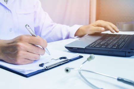 Doctor holding pen writing report Cancer Treatment Plan on desk with sunset light.Selective focusの写真素材