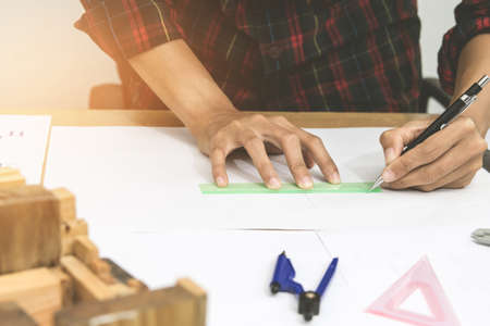 Concept architects,engineer holding pen pointing equipment architects On the desk with a blueprint in the office, Vintage, Sunset light.Selective Focusの写真素材