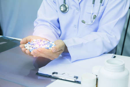 Healthcare and medical concept . Doctor in uniform holding white and blue capsule pill in office at hospital,Selective focusの写真素材