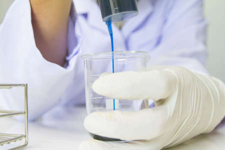 Close up. Medical or male medical in laboratory room research performs tests with blue liquid, Experimental Drug Treatmentの写真素材