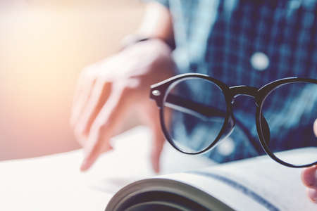 Man sitting and holding glasses on wood chair , reading bookの写真素材