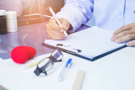 Doctor holding pen writing report Cancer Treatment Plan on desk with sunset light.Selective focusの写真素材